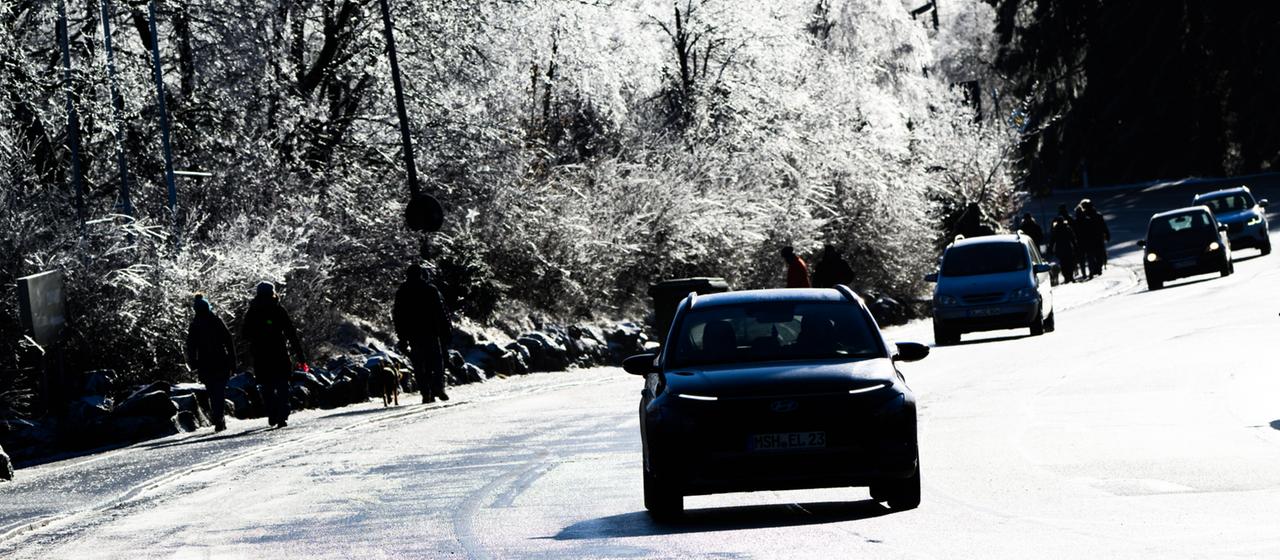 Autos fahren auf einer von Schnee bedeckten Fahrbahn durch den Wald
