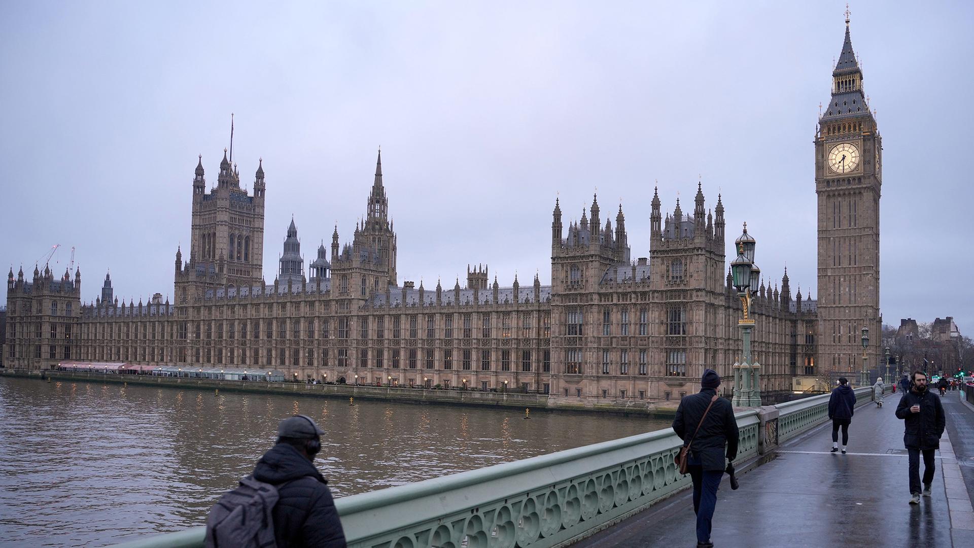 Fußgänger überqueren die Westminster Bridge - im Hintergrund ist der Westminster-Palast zu sehen. | Kin Cheung/AP/dpa