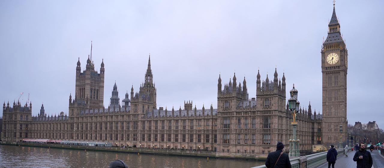 Fußgänger überqueren die Westminster Bridge - im Hintergrund ist der Westminster-Palast zu sehen.