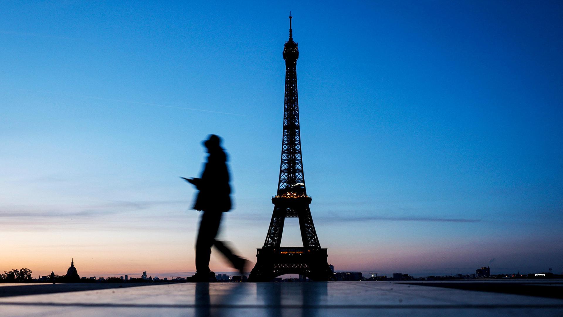 Ein Mann geht am Morgen vor dem Eifelturm. | AFP