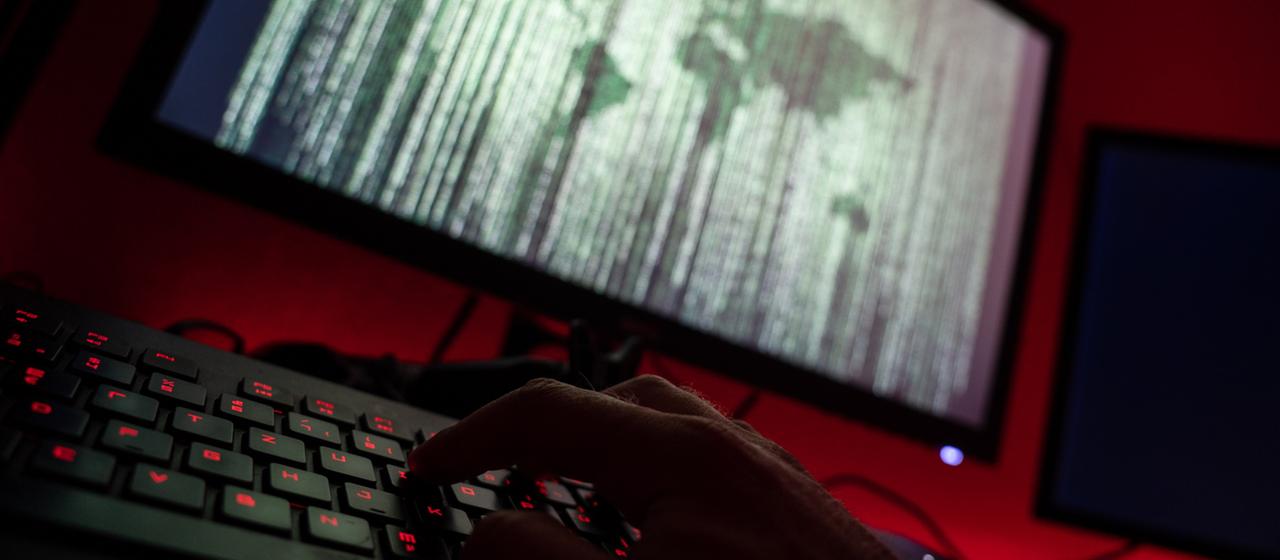 Ein Mann sitzt am Rechner und tippt auf einer Tastatur.