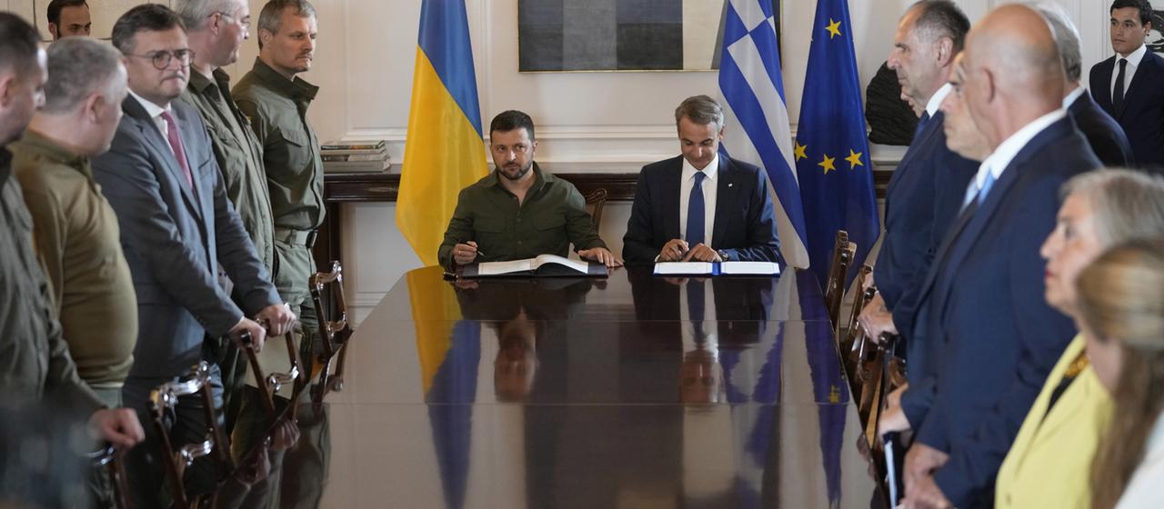Wolodymyr Selenskyj (Mitte l), Präsident der Ukraine, und Kyriakos Mitsotakis (Mitte r), Ministerpräsident von Griechenland, unterzeichnen während ihres Treffens in Athen ein Abkommen.