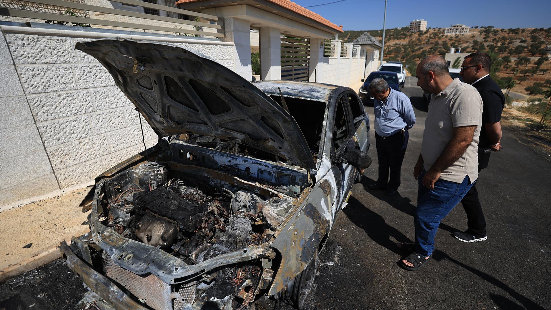 Anwohner inspizieren ein verbranntes Auto im palästinensischen christlichen Dorf Taybeh. | EPA