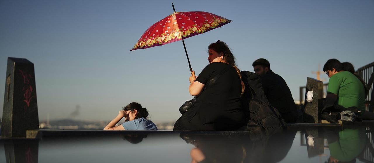 Eine Frau schützt sich an einem heißen Sommertag in Istanbul mit einem Schirm vor der Sonne.