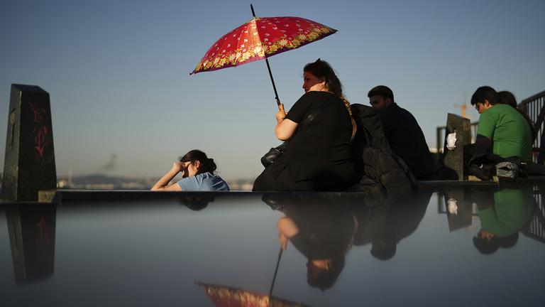 Eine Frau schützt sich an einem heißen Sommertag in Istanbul mit einem Schirm vor der Sonne.