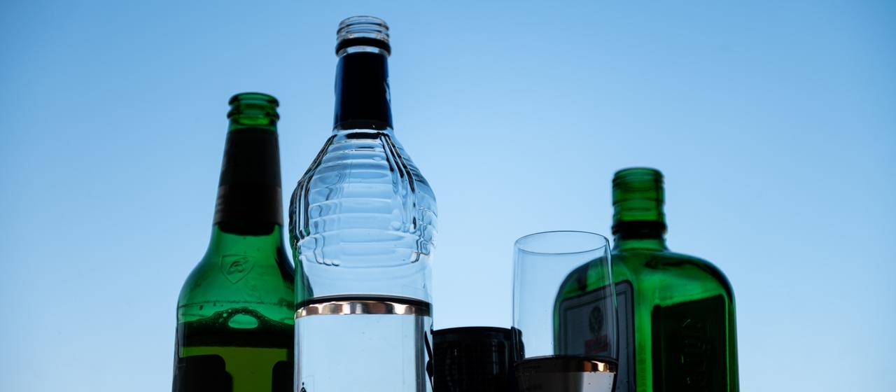 Various alcoholic drinks stand in front of a blue sky.