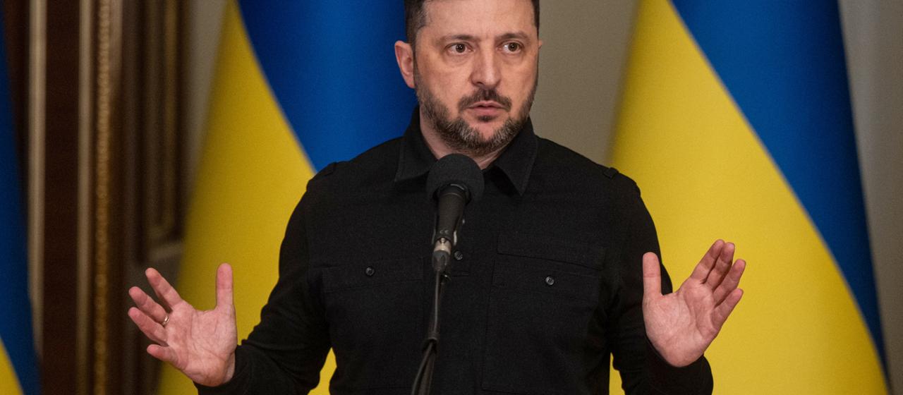 Wolodymyr Selenskyj vor zwei ukrainischen Landesflaggen.