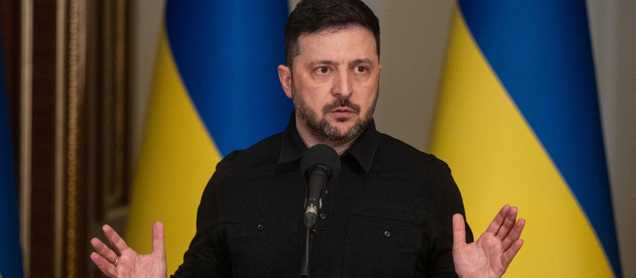 Wolodymyr Selenskyj vor zwei ukrainischen Landesflaggen.