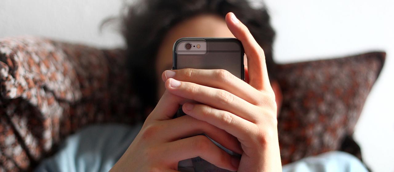 Ein Jugendlicher hält ein Handy in den Händen.
