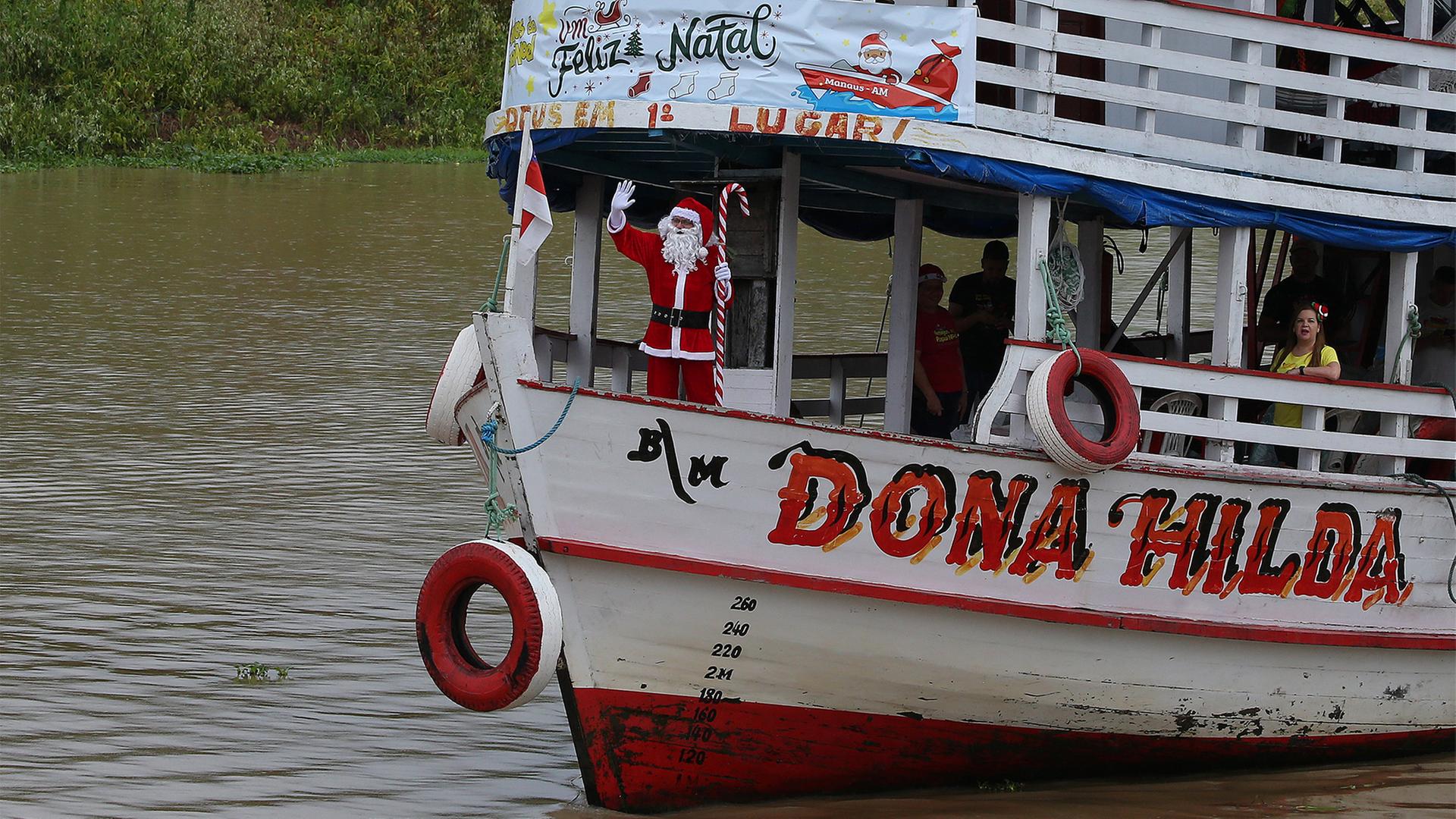 EIn als Weihnachtsmann verkleideter Mann winkt von einem Schiff. | dpa