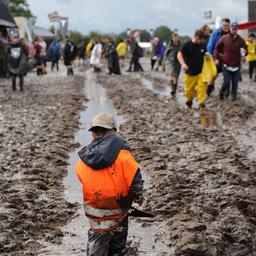 Metal-Fans sind auf dem schlammigen Festivalgelände unterwegs.