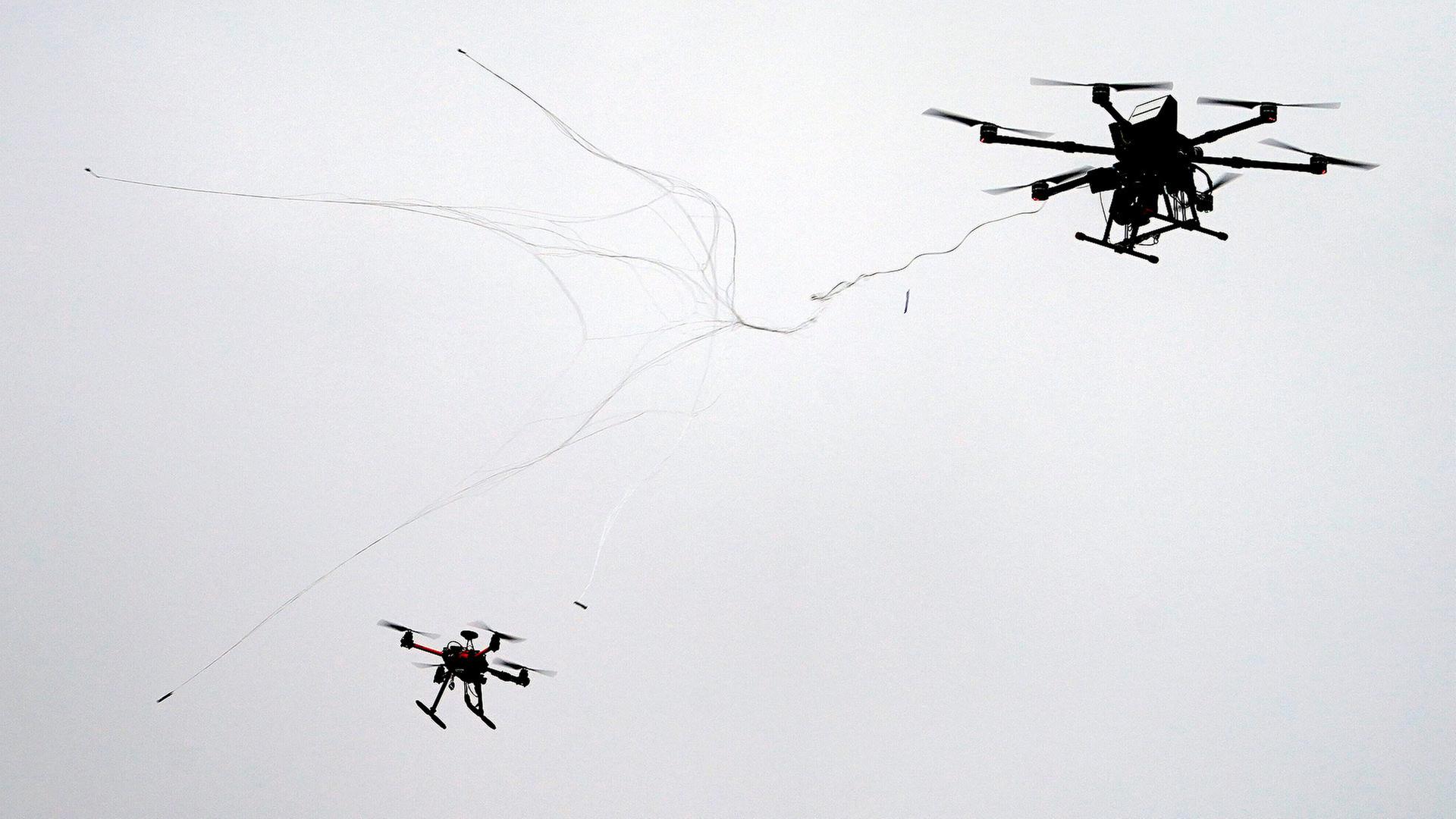 Eine Abwehrdrohne (r) schießt ein Netz auf eine kleine Drohne während einer Übung auf dem Gelände der Universität der Bundeswehr. | picture alliance/dpa