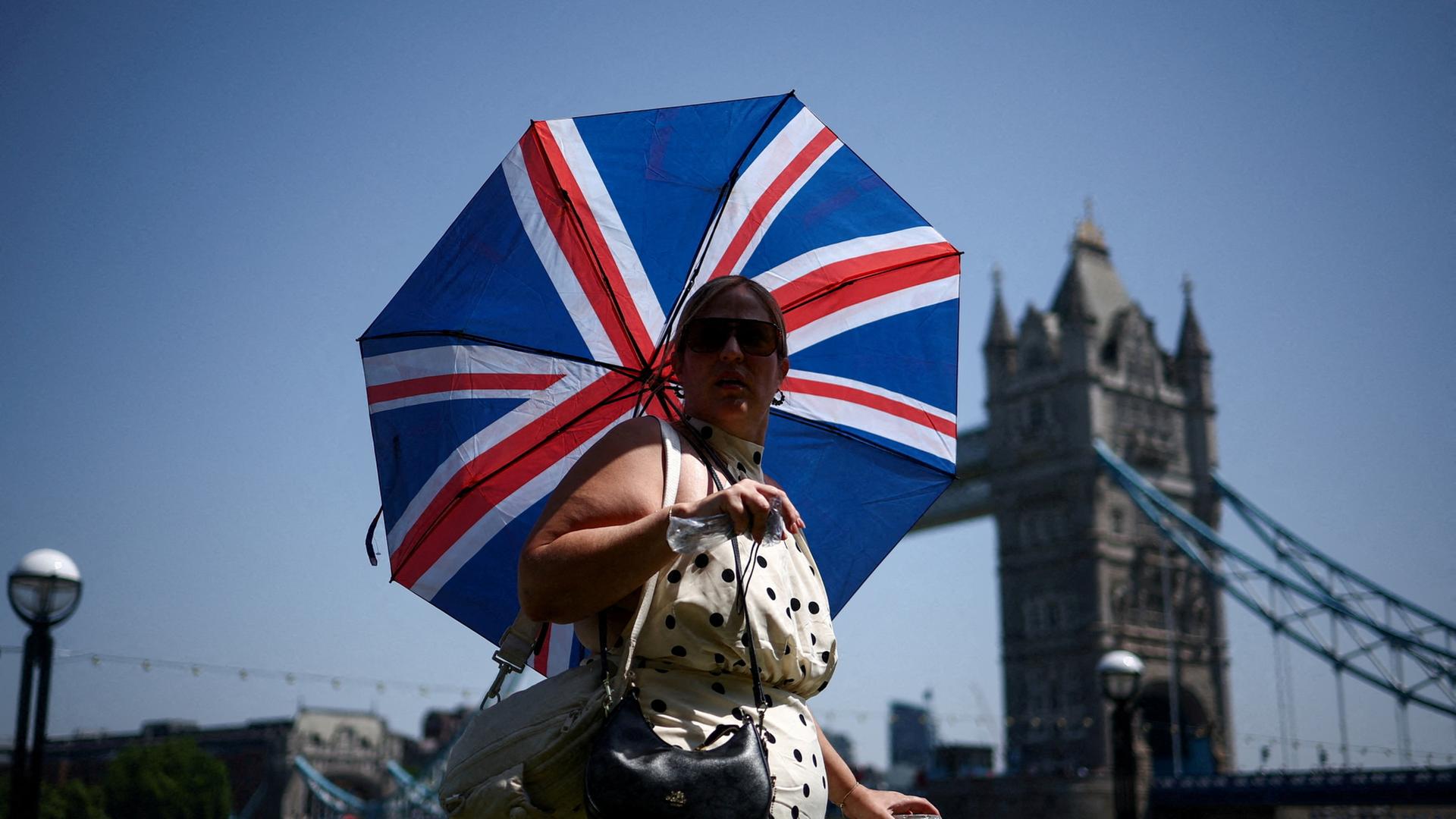 Eine Frau, die sich vor der Hitze mit einem Regenschirm schützt, in London | REUTERS