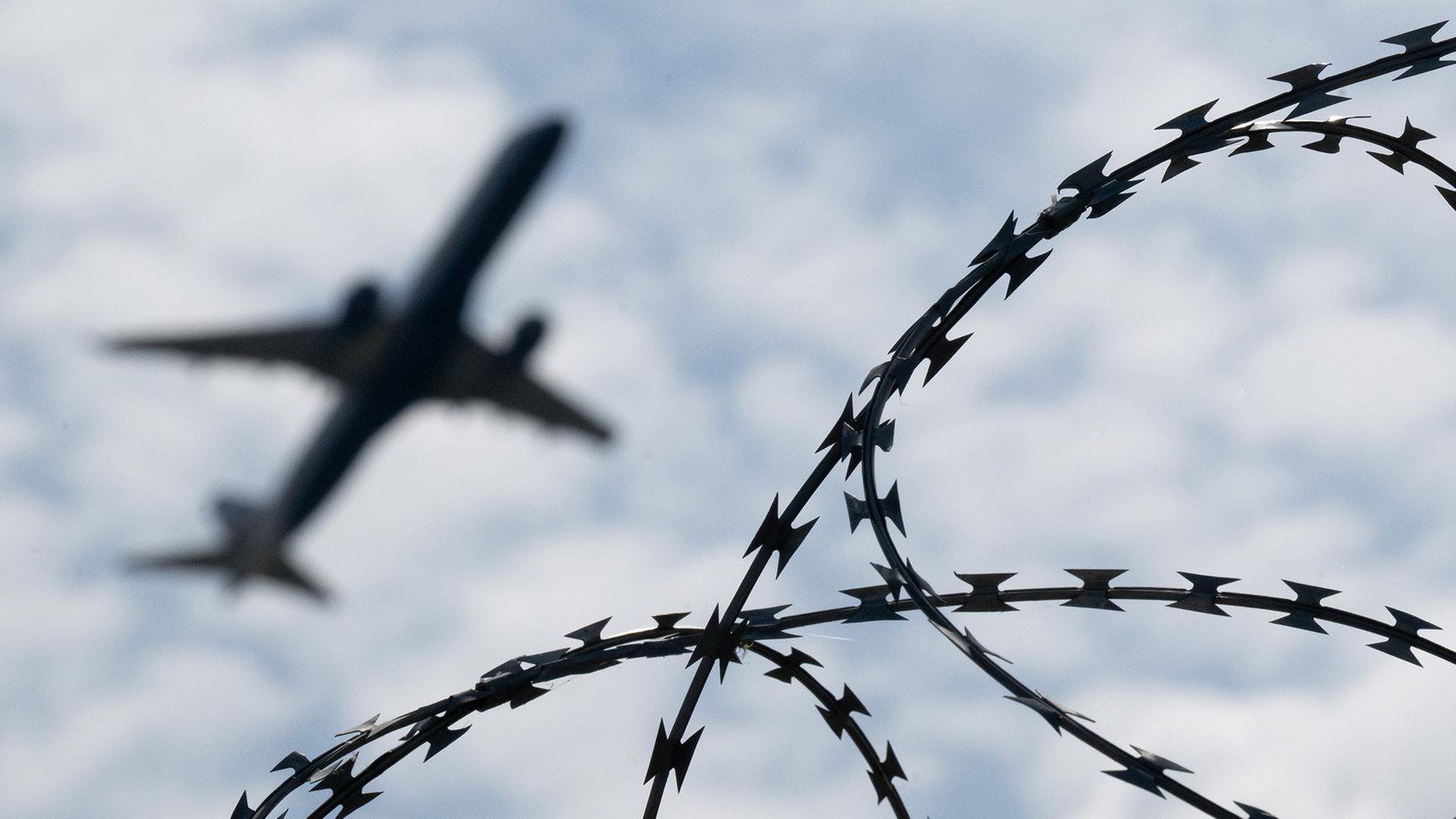 Ein Flugzeug hebt hinter einem Zaun mit Natodraht ab. | dpa
