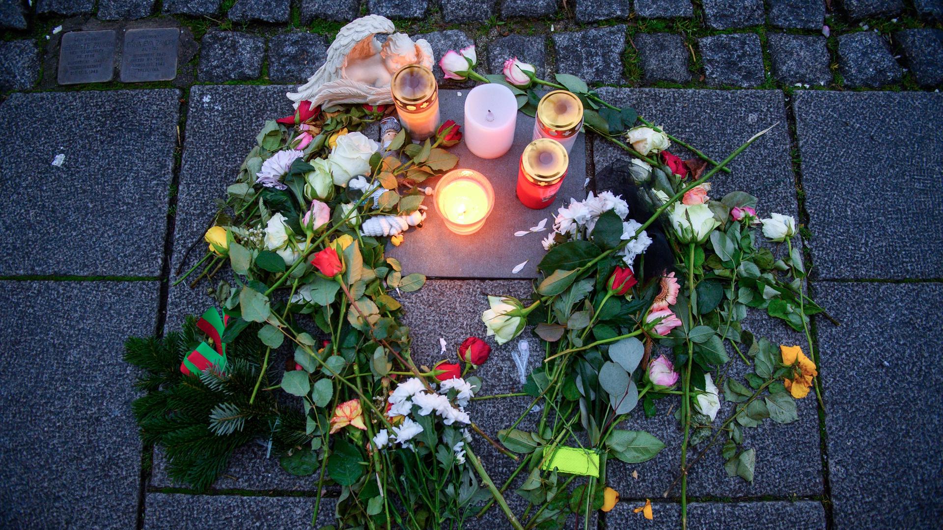 Kerzen und Blumen umgeben eine Gedenkplatte im Gehweg, die an ein Opfer des Anschlags auf den Magdeburger Weihnachtsmarkt erinnert.  | dpa