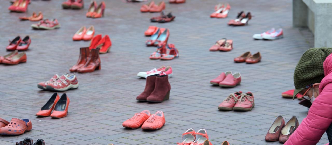 Eine Frau fotografiert rote Schuhe, die in Potsdam vor dem Landtag aufgestellt sind.