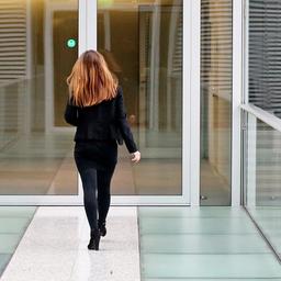 Eine Geschäftsfrau geht einen Gang in einer Konzernzentrale entlang