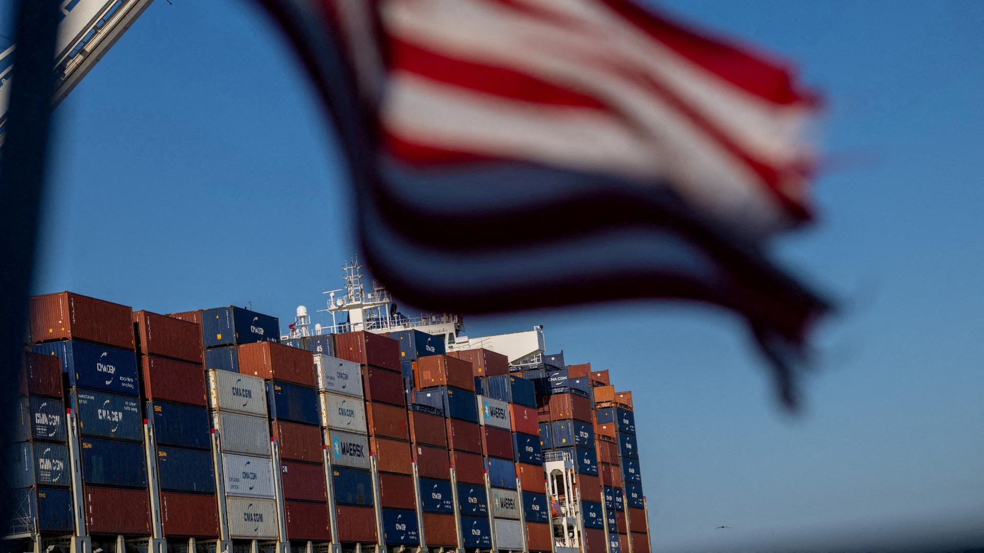 Vor einem mit Containern beladenes Frachtschiff weht die US-Flagge. | CB