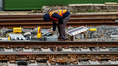 Ein Bauarbeiter in Warnweste steht in einem Gleisbett