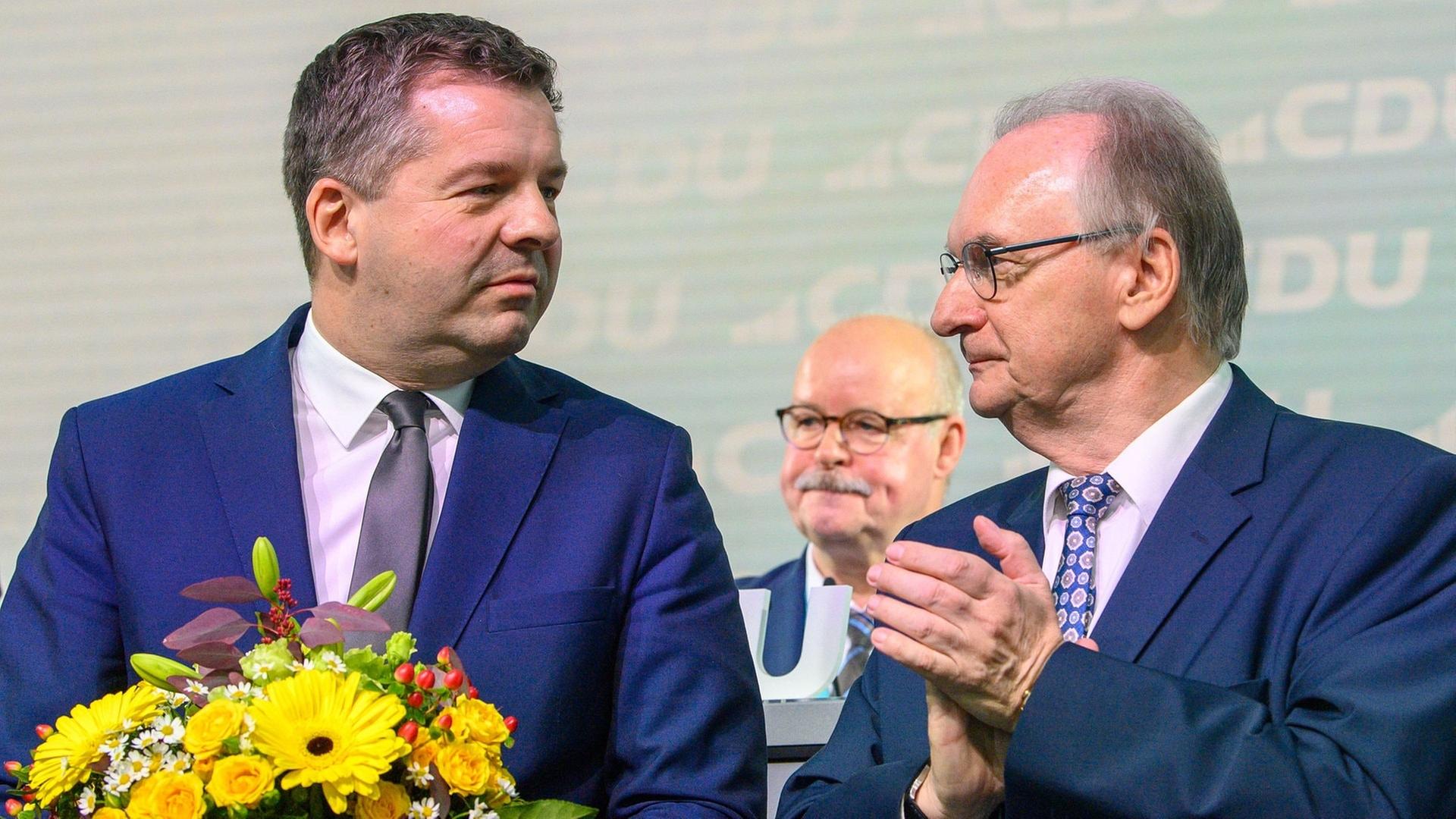 Sven Schulze (l), Vorsitzender der CDU Sachsen-Anhalt und Spizenkandidat der CDU bei der Landtagswahl 2026 steht nach seiner Wiederwahl mit Blumen auf der Bühne des Landesparteitages der CDU Sachsen-Anhalt. Neben ihm steht Reiner haseloff (CDU), Ministerpräsident des Landes Sachsen-Anhalt und applaudiert | picture alliance/dpa | Klaus-Dietmar Gabbert