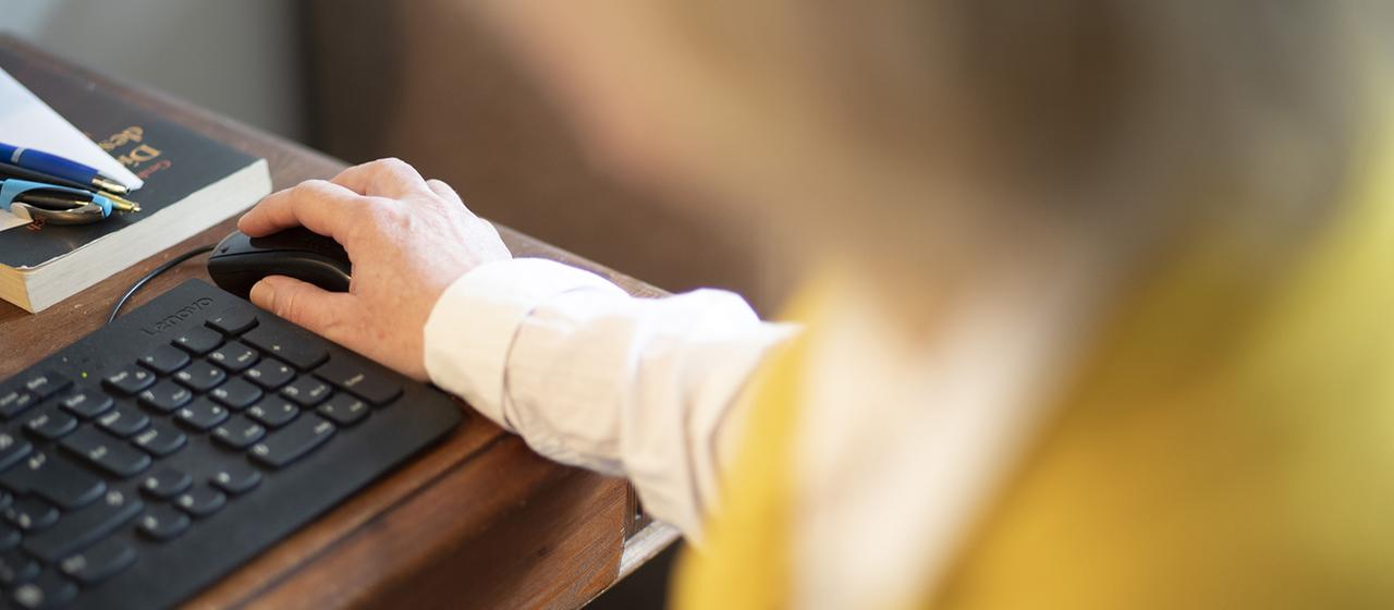 Eine Frau bedient eine Maus neben einer Computertastatur.