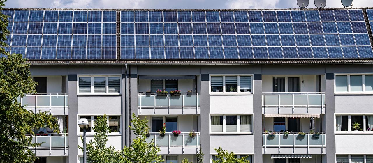 Mehrfamilienhaus mit Solaranlagen auf dem Dach.
