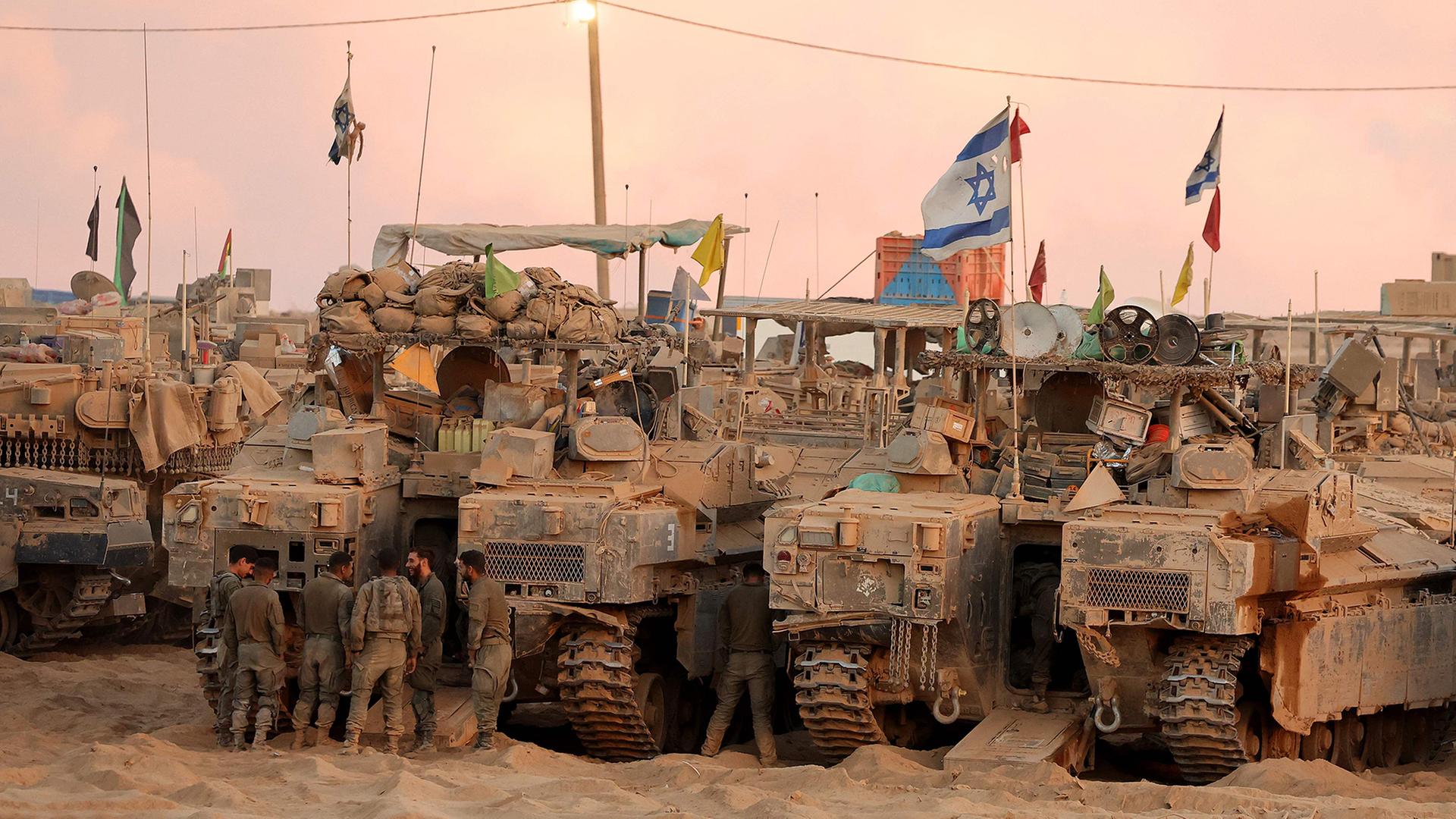Israelische Soldaten versammeln sich in der Nhe von gepanzerten Fahrzeugen an einer Position entlang des Grenzzauns zwischen Israel und Gaza. | AFP
