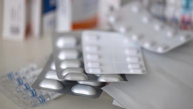 Mehrere Packungen mit Tabletten, Pflastern und Tropfen liegen auf einem Tisch.