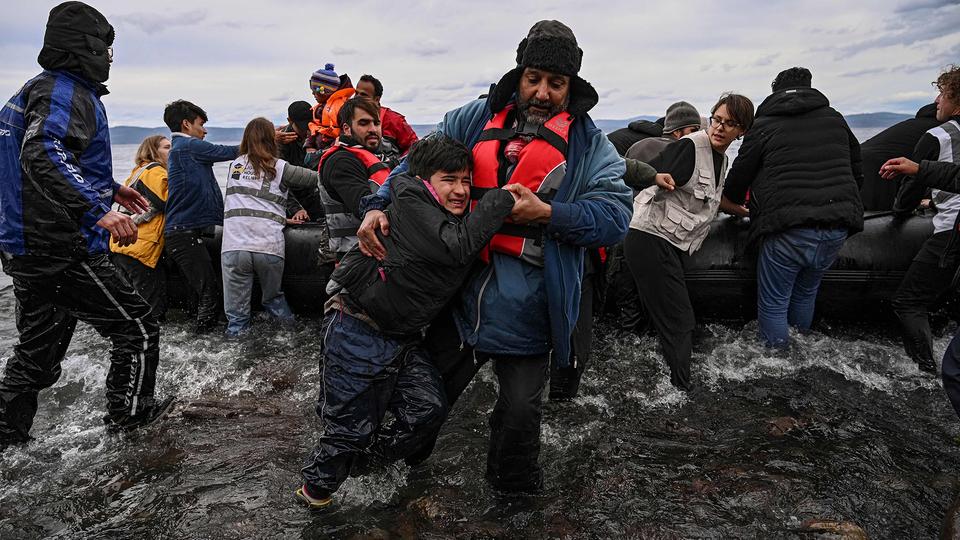 Ein Mann hilft einem Jungen beim verlassen eines Schlauchbootes, Lesbos/Griechenland.