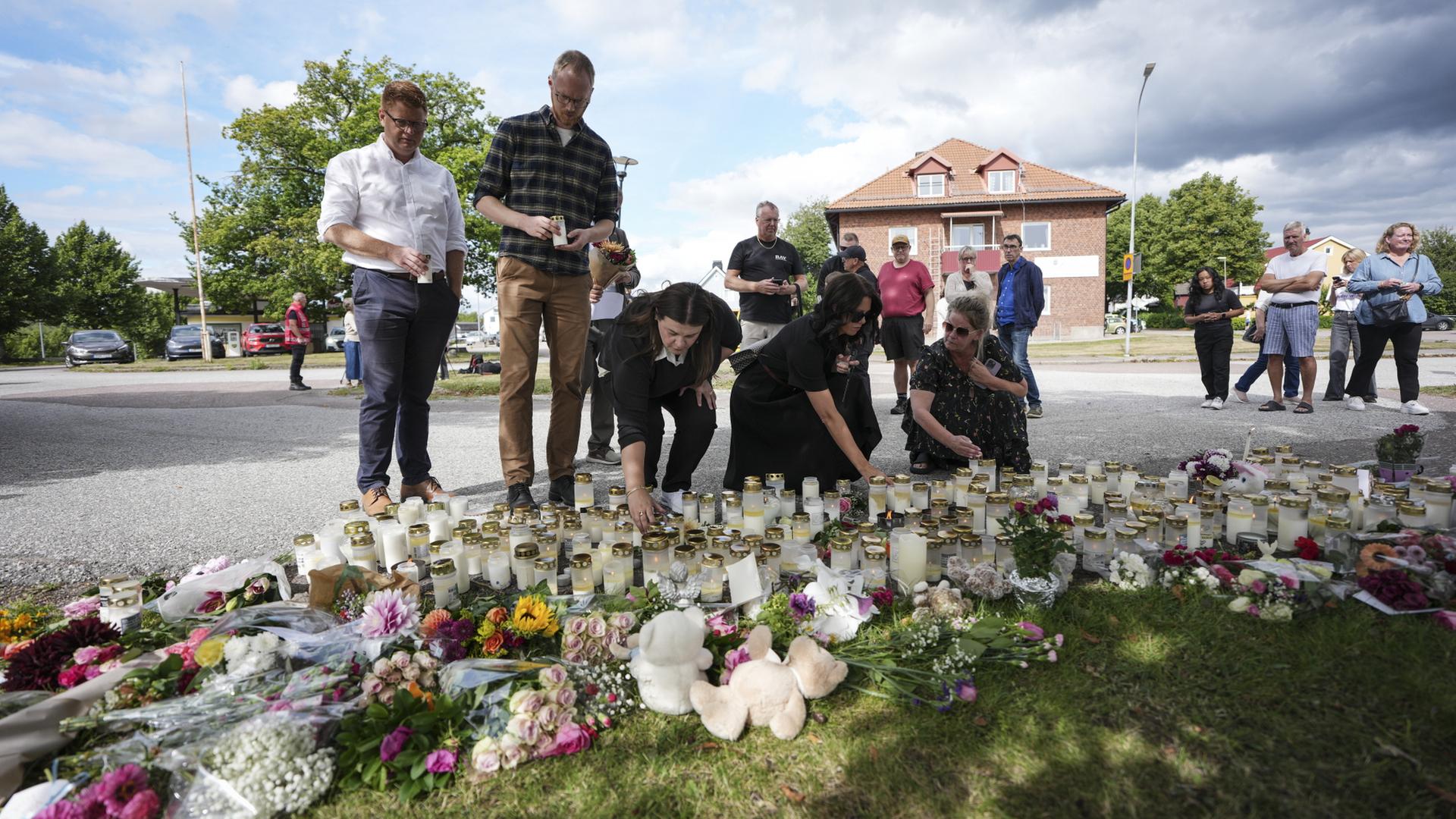 Menschen legen Blumen und Kerzen an einem improvisierten Denkmal vor einer Schule in Fagersta, Schweden, nieder. | EPA