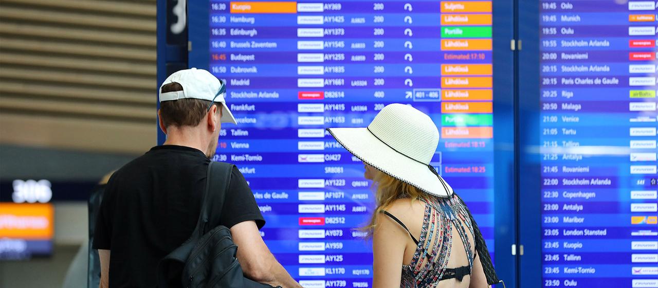 Reisende an einem Flughafen mit schauen auf die Anzeigetafel mit den Abflugszeiten.