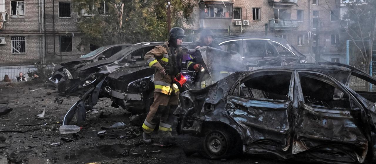 Ein Feuerwehrmann ist in Saporischschja (Ukraine) nach einem Angriff an ausgebrannten Autos im Einsatz.