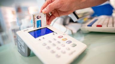 Eine Versichertenkarte wird in ein Lesegerät gesteckt.