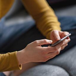 Eine Frau hält ein Smartphone in der Hand. 