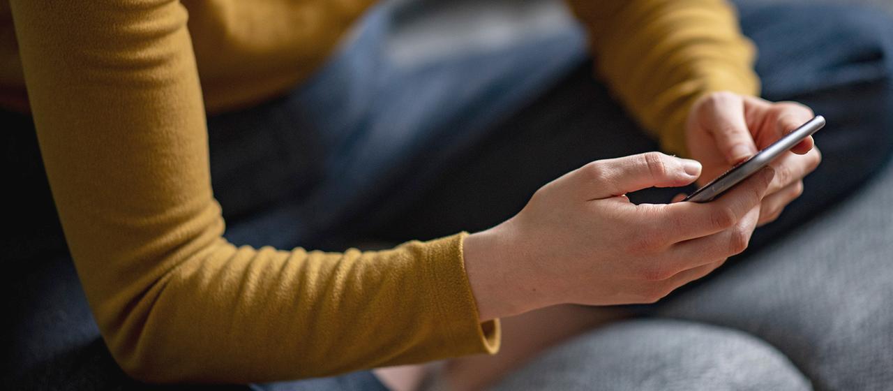 Eine Frau hält ein Smartphone in der Hand. 