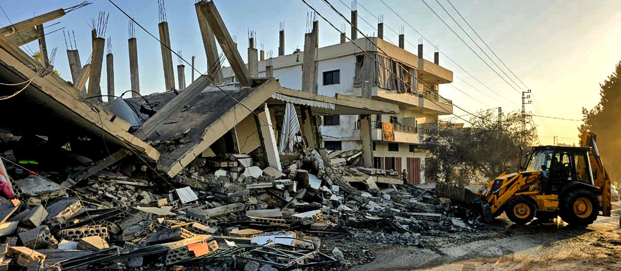 Ein Raupenfahrzeug beseitigt die Trümmer eines Hauses im Libanon.