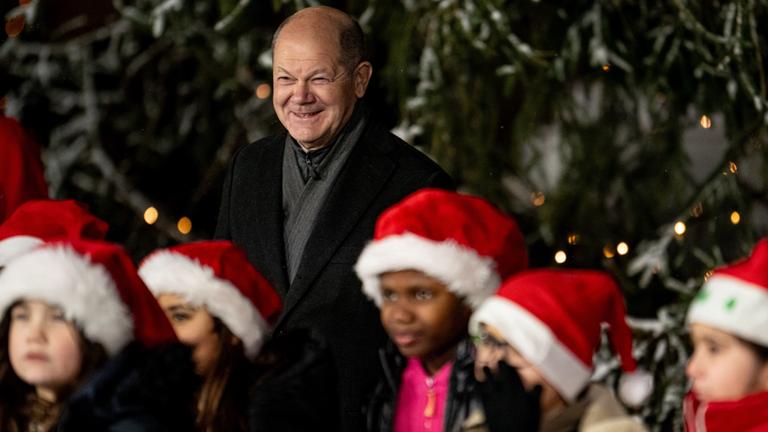 Olaf Scholz mit Kindern mit Weihnachtsmützen.