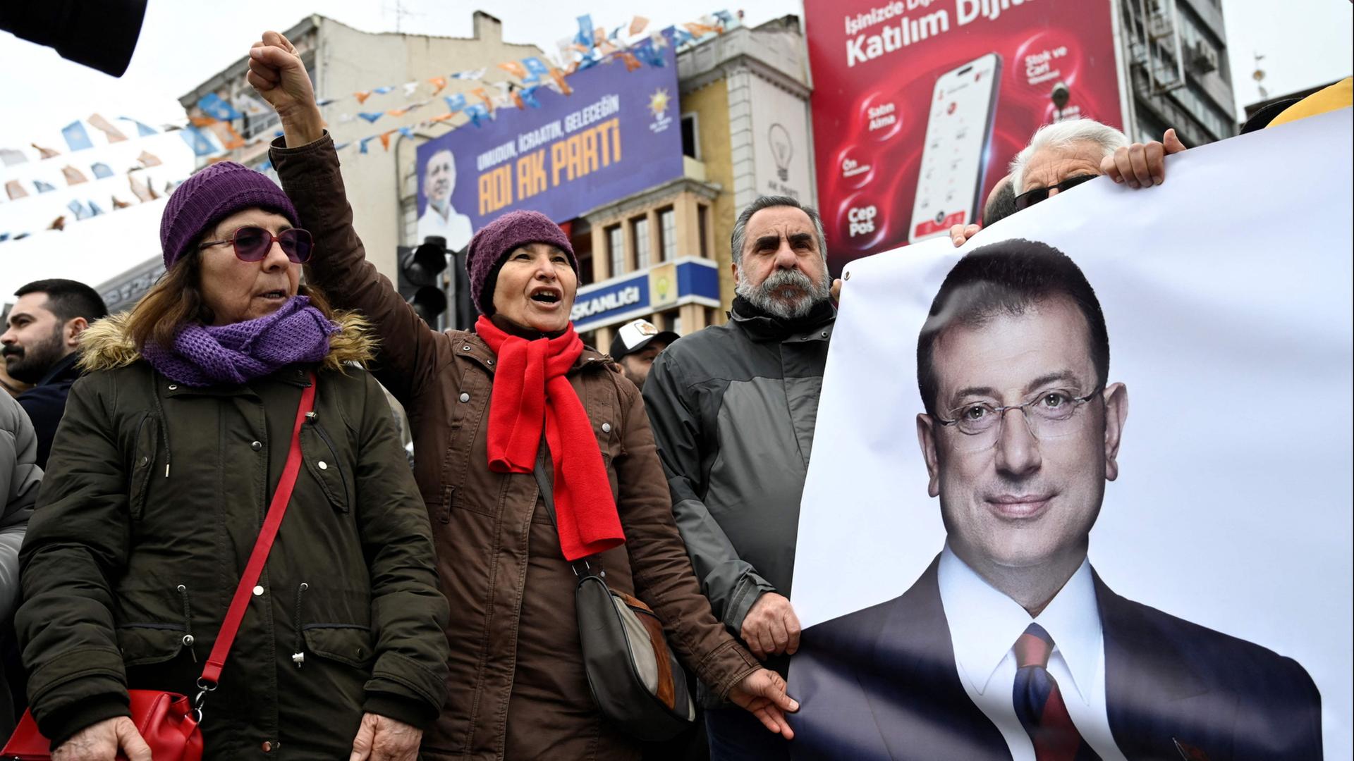 Menschen halten bei einem Protest in Istanbul gegen die Festnahme von Ekrem Imamoğlu ein Plakat mit seinem Bild. | AFP