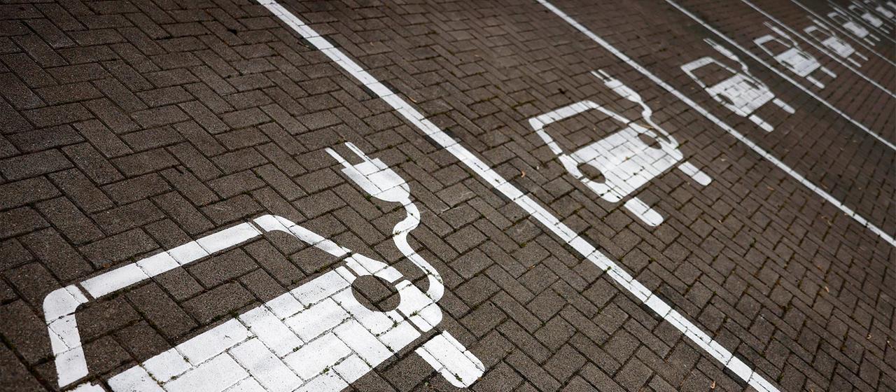 Piktogramme mit Autos, aus denen ein Stromkabel ragt, markieren Parkplätze mit Ladesäulen, an denen Elektro-Autos ihren Akku laden können.