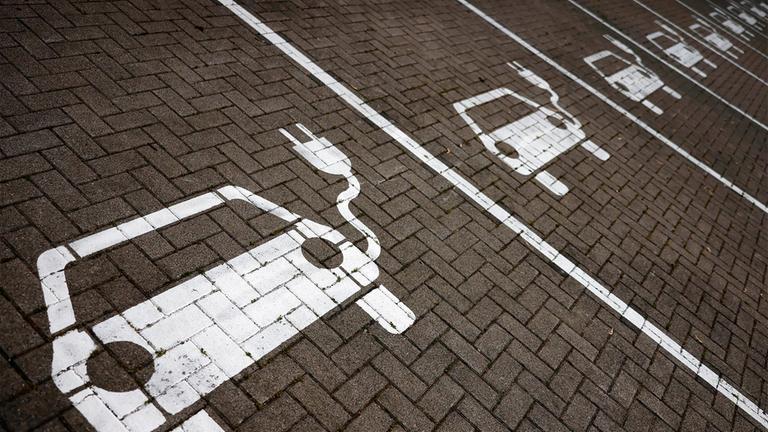 Piktogramme mit Autos, aus denen ein Stromkabel ragt, markieren Parkplätze mit Ladesäulen, an denen Elektro-Autos ihren Akku laden können.