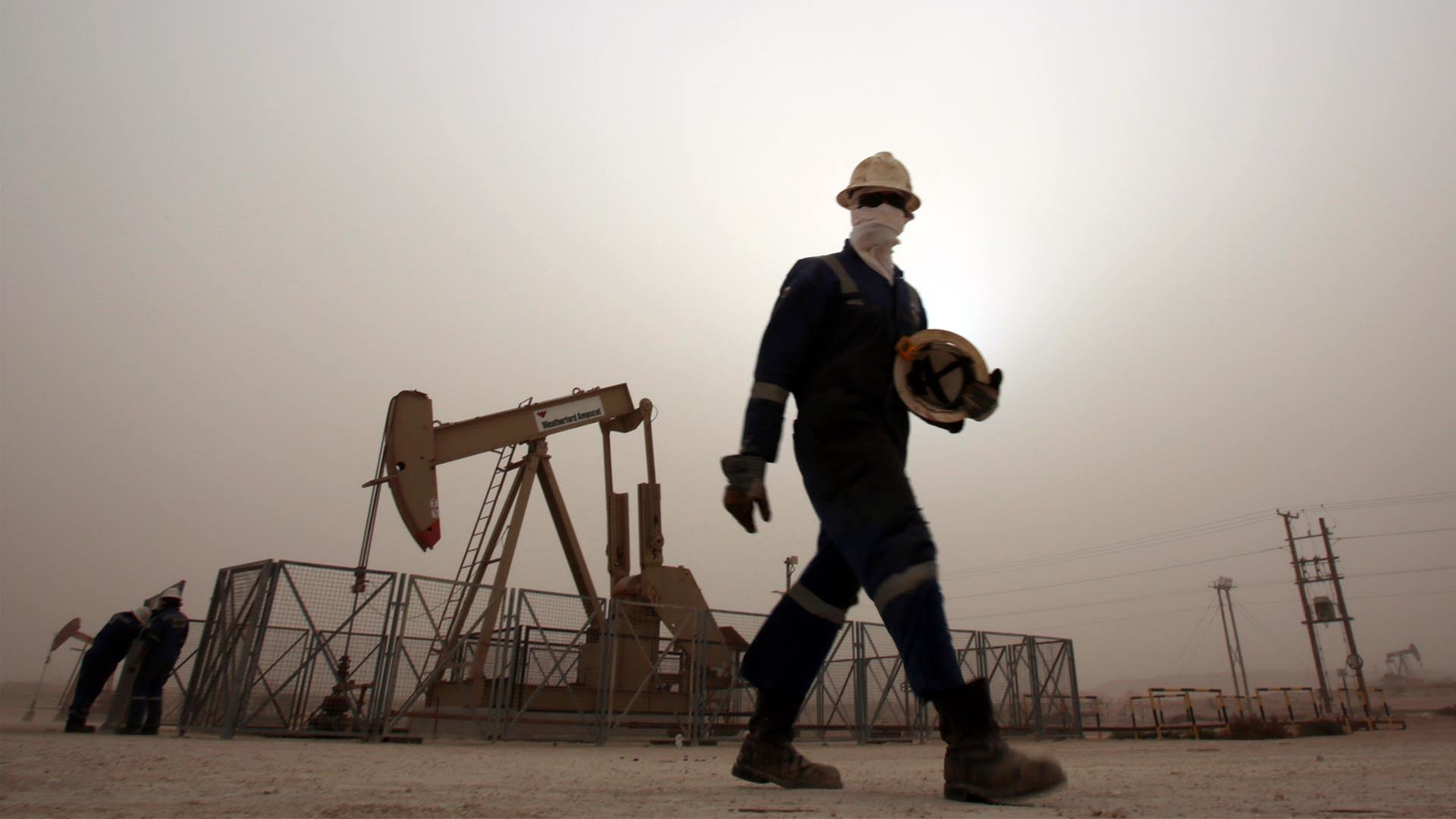 Ein Ölarbeiter vor einer Ölpumpe in Bahrain. | picture alliance / AP Photo