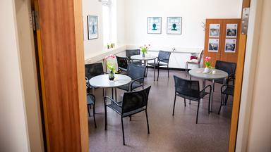 Blick in den Gruppenraum einer Hamburger Psychiatrie mit Stühlen, die um runde Tische gruppiert sind.