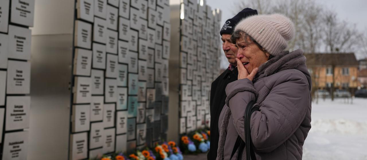 Verwandte von in Butscha Ermordeten vor einer Gedenkstätte.