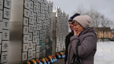 Verwandte von in Butscha Ermordeten vor einer Gedenkstätte.
