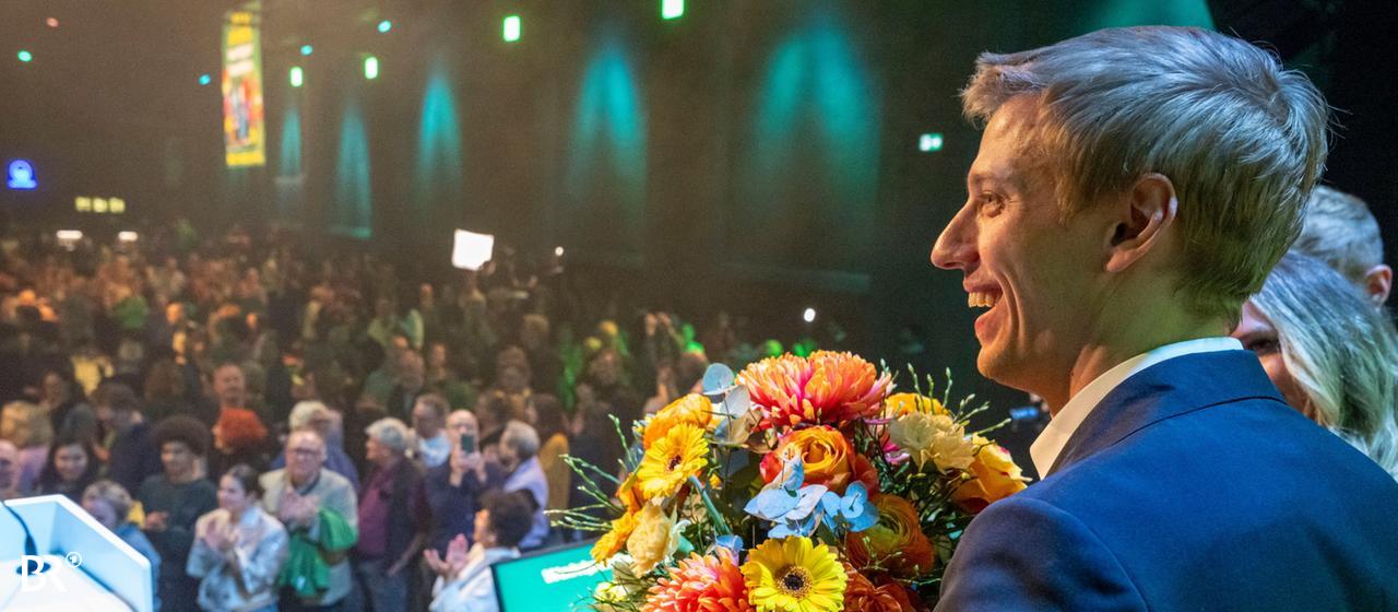 Der Grüne OB Kandidat in München, Krause steht mit Blumen auf einer Bühne