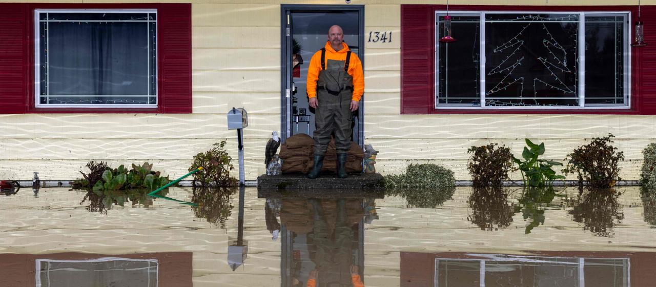 Ein Mann steht im Eingang seines vom Wasser umschlossenen Hauses in Burlington, USA.