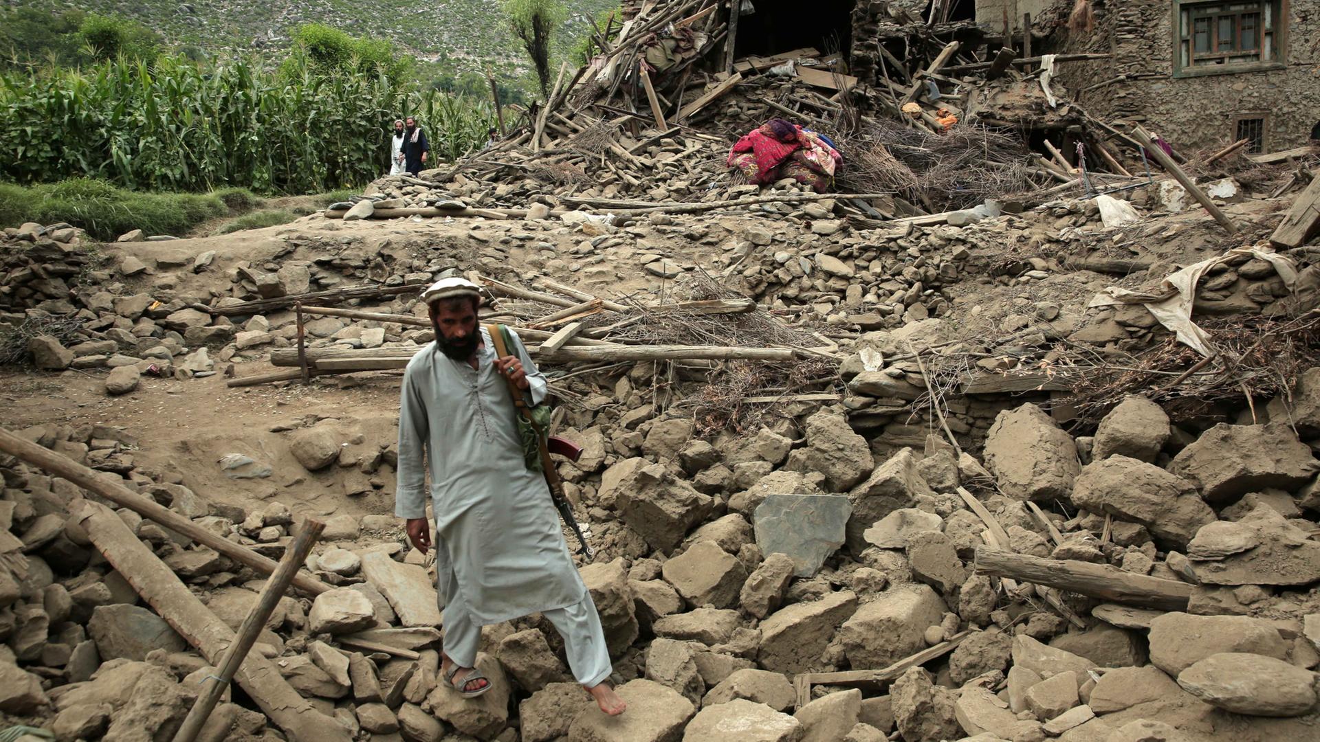 Ein Mann läuft nach einem Erdbeben in Kunar, Afghanistan, über Trümmer neben einem beschädigten Haus | EPA