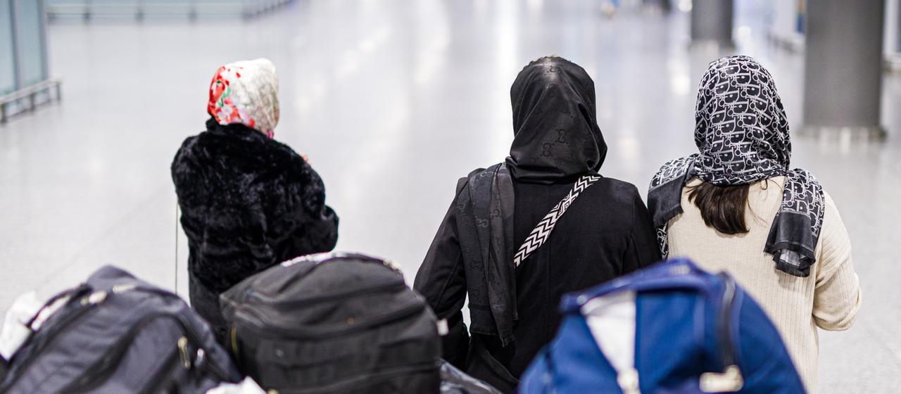 Menschen aus Afghanistan warten mit ihrem Gepäck im Flughafen Hannover-Langenhagen