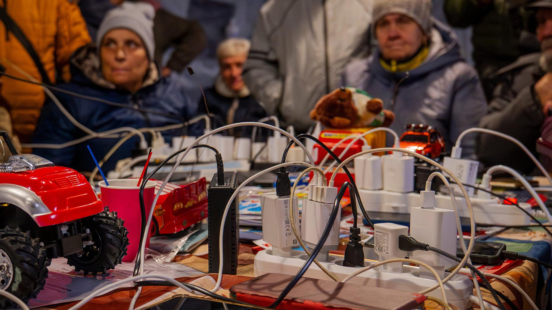 Menschen laden ihre Handys in einem Zelt in Tschernihiw auf. | AP