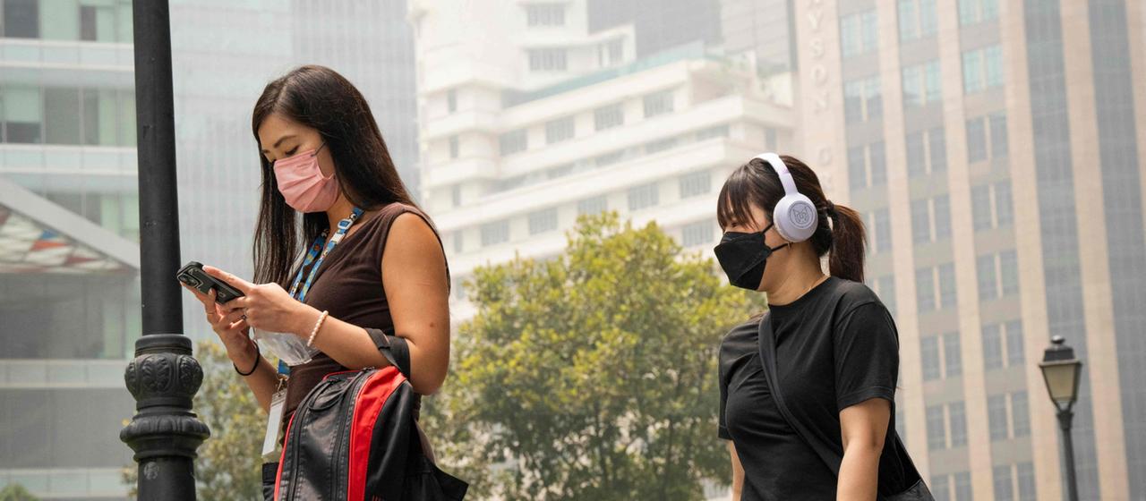 Zwei Frauen gehen mit Gesichtsmasken durch das Geschäftsviertel von Singapur.